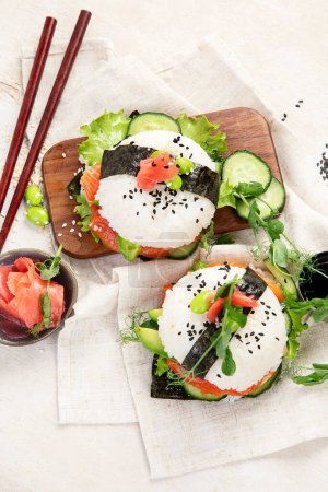 Téléchargez les photos : Nourriture hybride moderne. Burger sushi au saumon, riz blanc, avocat, concombre. Vue du dessus - en image libre de droit