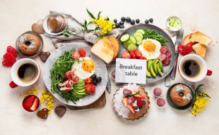 Foto de Desayuno servido con café, panadería fresca, huevos, ensalada, carne y frutas. Concepto de vacaciones. Vista superior. - Imagen libre de derechos