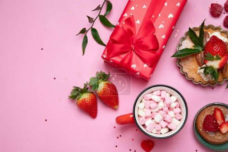 Foto de Fondo rosa festivo con cupcake, fresas, chocolates, bebida caliente. Celebración de cumpleaños. Vista superior, espacio de copia - Imagen libre de derechos