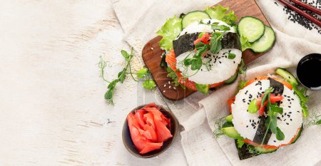 Téléchargez les photos : Nourriture hybride moderne. Burger sushi au saumon, riz blanc, avocat, concombre. Vue du dessus, espace de copie, bannière - en image libre de droit