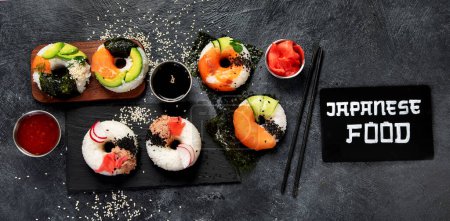 Foto de Rosquillas de sushi sobre un fondo oscuro. Comida de tendencia híbrida. Vista superior, banner - Imagen libre de derechos