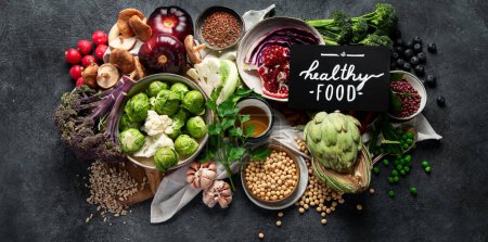 Téléchargez les photos : Nourriture végétalienne. Poivre, brocoli, chou, ail, champignons, grenade sur fond sombre. Vue du dessus, bannière - en image libre de droit