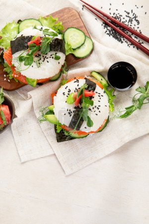 Téléchargez les photos : Nourriture hybride moderne. Burger sushi au saumon, riz blanc, avocat, concombre. Vue du dessus, espace de copie - en image libre de droit