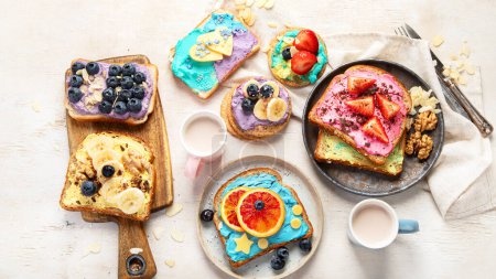 Foto de Desayuno dulce con taza de cacao. Tostadas con queso crema, plátano, fresas, arándanos. Vista superior - Imagen libre de derechos