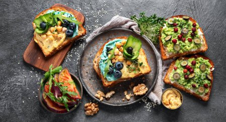 Photo for Vegetarian toasts with hummus, blueberry, avocado, tomato. delicious vegan breakfast on dark background. Top view - Royalty Free Image