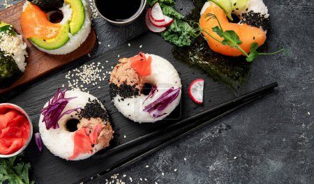 Sushi-Donuts auf dunklem Hintergrund. Hybrid-Trendfood. Ansicht von oben, Kopierraum