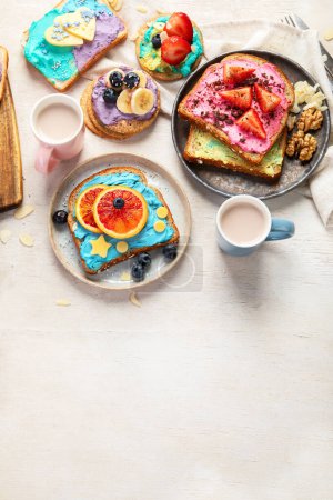 Foto de Desayuno dulce con taza de cacao. Tostadas con queso crema, plátano, fresas, arándanos. Vista superior, espacio de copia - Imagen libre de derechos