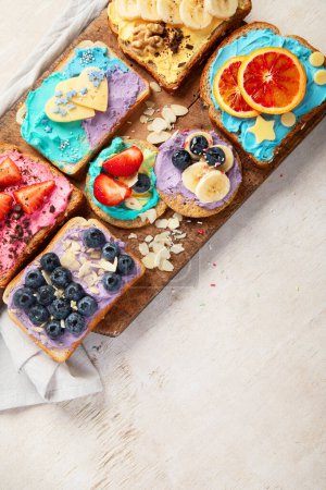 Foto de Dulce desayuno. Brindis coloridos con frutas y bayas. Concepto de comida infantil. Vista superior, espacio de copia - Imagen libre de derechos