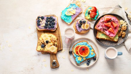 Foto de Desayuno dulce con taza de cacao. Tostadas con queso crema, plátano, fresas, arándanos. Vista superior, espacio de copia - Imagen libre de derechos
