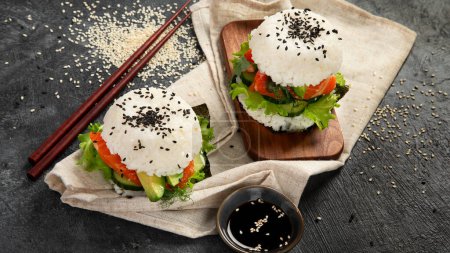 Téléchargez les photos : Hamburger de sushi asiatique, sauce soja, baguette sur fond sombre. Alimentation hybride tendance. - en image libre de droit