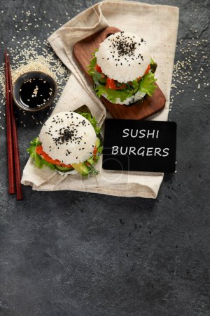 Foto de Hamburguesa asiática de sushi, salsa de soja, palillo sobre fondo oscuro. Comida híbrida de moda. Vista superior, espacio de copia - Imagen libre de derechos