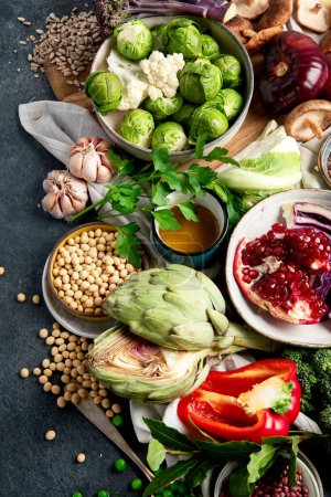 Téléchargez les photos : Nourriture végétalienne. Poivre, brocoli, chou, ail, champignons, grenade sur fond sombre. Vue du dessus - en image libre de droit