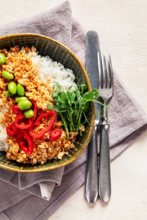 Foto de Comida vegana. Carne de soja, arroz blanco, frijoles, pimiento rojo sobre fondo de madera clara. Vista superior - Imagen libre de derechos