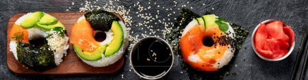 Foto de Rosquillas de sushi sobre un fondo oscuro. Comida de tendencia híbrida. Banner de vista superior - Imagen libre de derechos