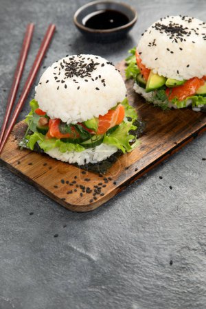 Foto de Hamburguesa asiática de sushi, salsa de soja, palillo sobre fondo oscuro. Comida híbrida de moda. Copiar espacio - Imagen libre de derechos