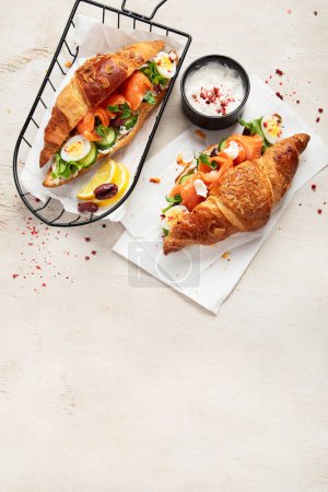 Photo for Salted healthy breakfast on light background. Fresh salmon croissant with cream cheese, cucumber, egg and salad. Top view, copy space - Royalty Free Image