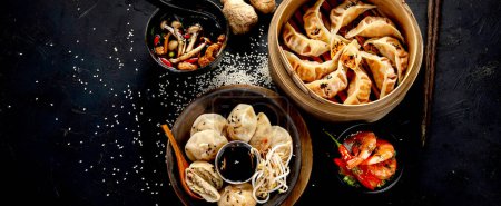Téléchargez les photos : Boulettes chinoises, sauce soja, champignons sur fond sombre. concept alimentaire asiatique traditionnel. Vue du dessus, bannière - en image libre de droit