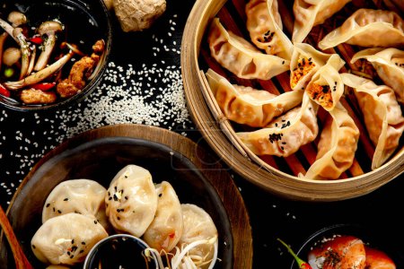 Téléchargez les photos : Boulettes chinoises, sauce soja, champignons sur fond sombre. concept alimentaire asiatique traditionnel. Vue du dessus - en image libre de droit