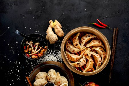 Téléchargez les photos : Boulettes chinoises, sauce soja, champignons sur fond sombre. concept alimentaire asiatique traditionnel. Vue du dessus - en image libre de droit