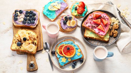 Foto de Desayuno dulce con taza de cacao. Tostadas con queso crema, plátano, fresas, arándanos. Vista superior - Imagen libre de derechos