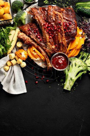 Foto de Costillas de cerdo con verduras sobre fondo negro. Comida para picnic concepto. Vista superior, espacio de copia - Imagen libre de derechos
