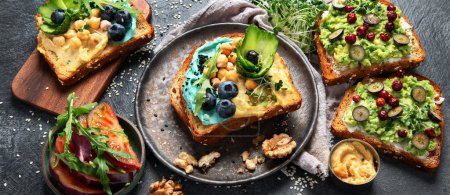 Photo for Vegetarian toasts with hummus, blueberry, avocado, tomato. delicious vegan breakfast on dark background. Banner - Royalty Free Image