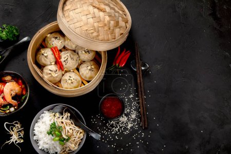 Téléchargez les photos : De la bouffe chinoise. Dumplings, sauce soja, crevettes sur fond noir. Déjeuner asiatique traditionnel. Vue du dessus, espace de copie - en image libre de droit