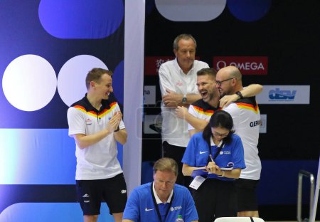 Foto de Berlín, Alemania - 22 de marzo de 2024: Christoph Bohm (C) y otros entrenadores alemanes reaccionan durante el Mixed 3m & 10m Team Event Final de la Copa Mundial de Buceo Acuático 2024 en Berlín. Alemania ganó el segundo lugar - Imagen libre de derechos