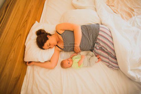 Foto de Mother and newborn baby sleep in the bed together - Imagen libre de derechos