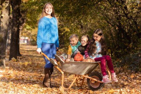 Photo for Mother have fun time with kids, use garden wheelbarrow with pumpkins. - Royalty Free Image