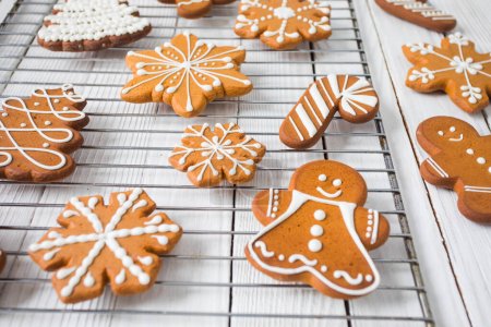 Téléchargez les photos : Biscuits au pain d'épice sur table en bois blanc, personnages de Noël et flocons de neige - en image libre de droit