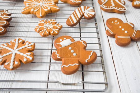 Biscuits au pain d'épice sur table en bois blanc, personnages de Noël et flocons de neige