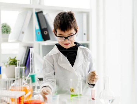 Photo for School boy wearing protection glasses doing chemistry experiment in elementary science class. Pupil with equipment tubes in lab - Royalty Free Image