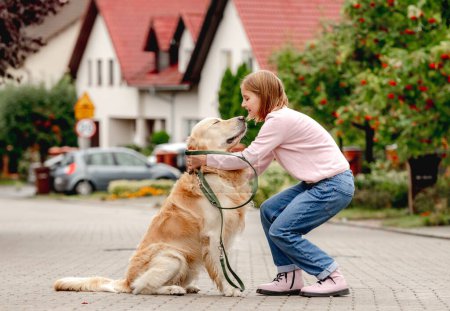 Photo for Preteen girl wear on golden retriever dog lace outdoors. Pretty kid child with purebred pet doggy walking at street - Royalty Free Image