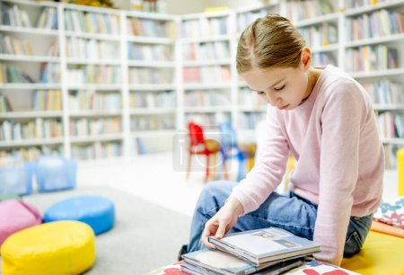 Téléchargez les photos : Jolie fille enfant lecture livre à la bibliothèque. Jeune fille mignonne pré-adolescente étudiant la littérature et faisant de la recherche pour l'école à biblioteque - en image libre de droit