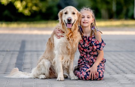 Téléchargez les photos : Preteen girl and her golden retriever dog on lace looking at camera. Female child kid with a purebred labrador doggy pet - en image libre de droit