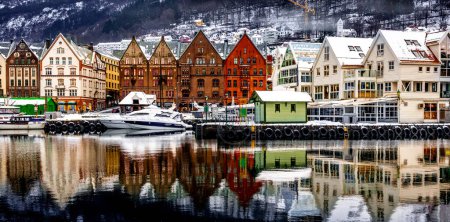 Foto de Invierno Bergen ciudad con famosos Bryggen UNESCO mercadería casas de madera en temporada de nieve. Panorama de edificios históricos del puerto en época de Navidad con reflejo mágico en el mar - Imagen libre de derechos