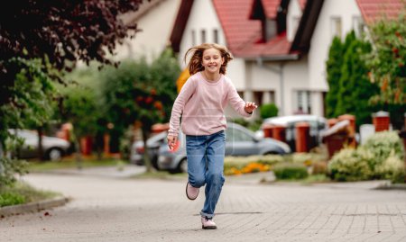 Photo for Preteen girl running outdoors and smiling. Cute pretty child kid having fun at street - Royalty Free Image