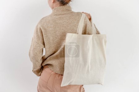 Foto de Girl holding cotton linen eco bag mockup, back view. Woman with environment friendly shopping handbag with empty copy space for business - Imagen libre de derechos
