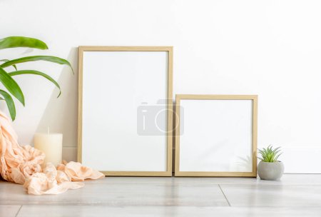 Foto de Wooden frame for photos. candle and plant in scandinavian interior mockup. Minimal template with empty picture blank at home - Imagen libre de derechos