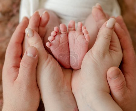 Téléchargez les photos : Newborn baby feet in parents hands making heart shape symbol of love. Family portrait with infant child kid barefoot legs - en image libre de droit