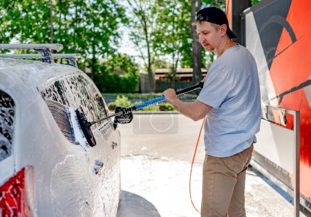 Foto de Un hombre lavando un coche en un auto-servicio de lavado de coches con un cepillo - Imagen libre de derechos