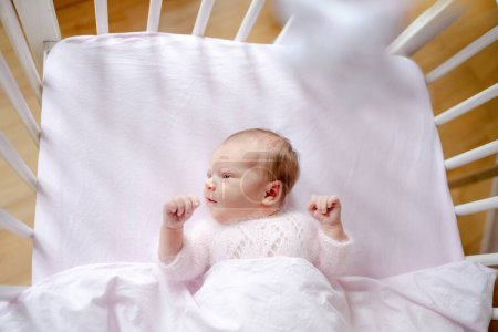 Téléchargez les photos : Nouveau-né bébé fille portant un chapeau tricoté couché dans le lit des enfants, vue d'en haut. Enfant en bas âge enfant dans le berceau portrait studio - en image libre de droit