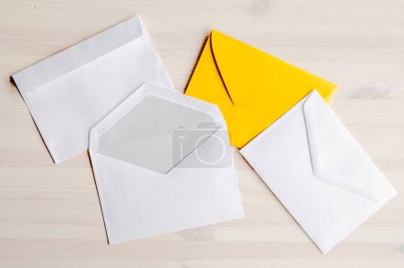 Photo for White and yellow envelopes for letter and correspondence lying on wooden table. Empty blank paper post delivery with copy space - Royalty Free Image