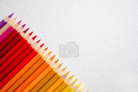 Photo for Colorful pencils red and orange set on watercolor paper with copy space closeup. Multicolor crayons pallete for artist inspiration - Royalty Free Image