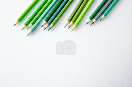 Foto de Lápices verdes colocados sobre papel acuarela. Paleta de crayones multicolor con espacio de copia para la inspiración del artista y el hobby - Imagen libre de derechos