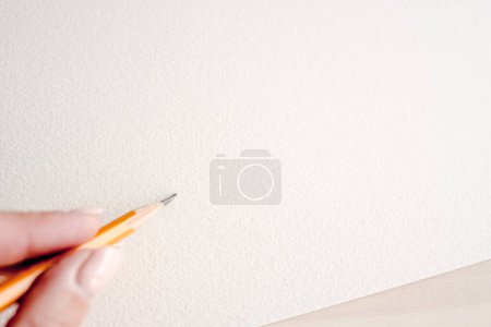 Foto de Mano de niña sosteniendo lápiz de grafito y dibujo boceto en papel acuarela. Dedos de artista con crayón durante el desarrollo de obras de arte - Imagen libre de derechos