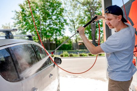Téléchargez les photos : Prise de vue d'un homme lavant sa voiture sous haute pression à l'extérieur. - en image libre de droit