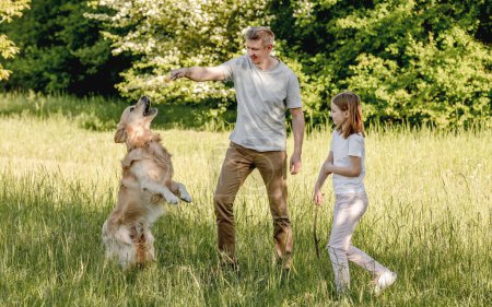 Téléchargez les photos : Dad and his daugter play with golden retriver dog - en image libre de droit