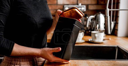 Photo for Girl opening tea black metal jar at kitchen to prepare hot natural beverage. Woman hands holding herbal drink container at home - Royalty Free Image
